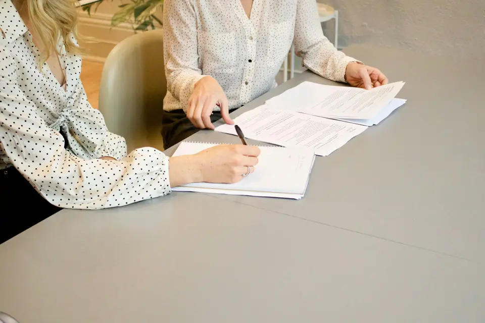 Dos personas revisan documentos sobre una mesa de trabajo