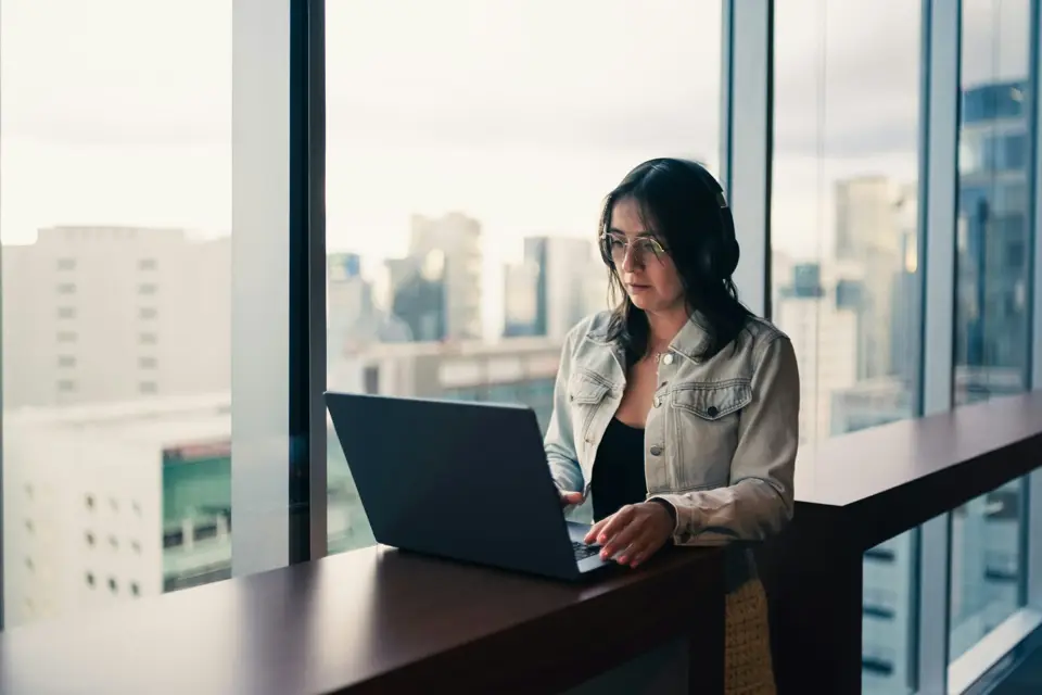 Profesionista trabajando en su computadora junto a la ventana de una oficina